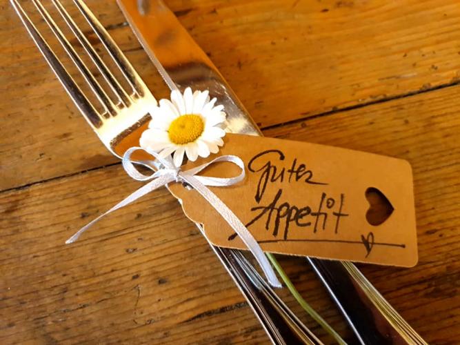 Besteck mit einer Blume und einem Schild mit dem Text: 'Guten Appetit!'